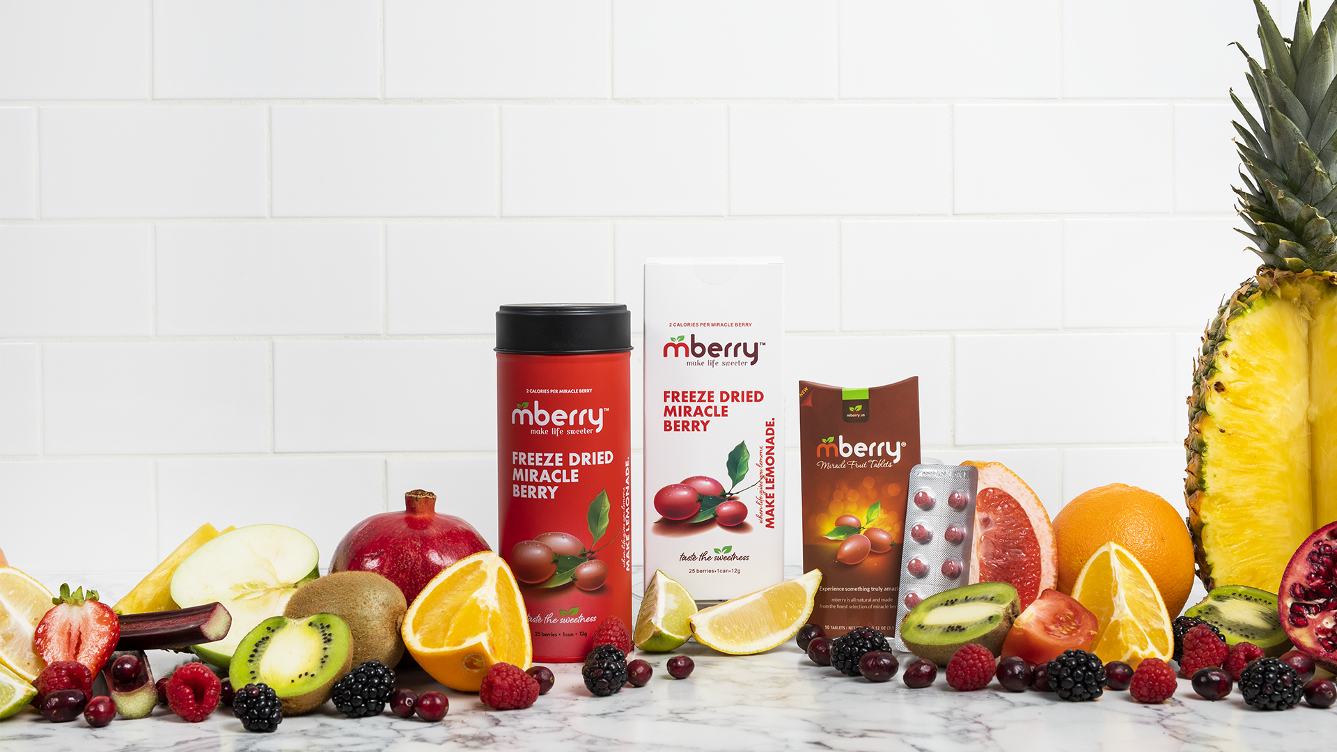 mberry miracle fruit tablets with mberry freeze dried miracle berries surrounded by differnt types of fruits such as pineapple, kiwi, orange, grapefruit, etc.