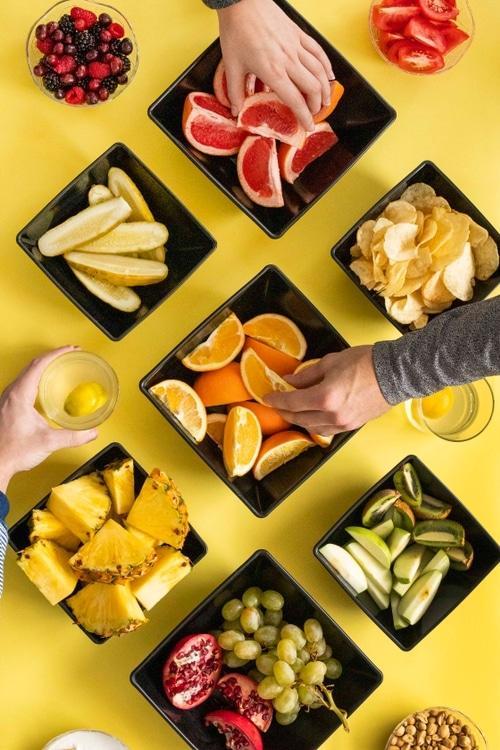 flavor tripping part on yellow table with hands reaching for grapefruit oranges pineapple and drinks