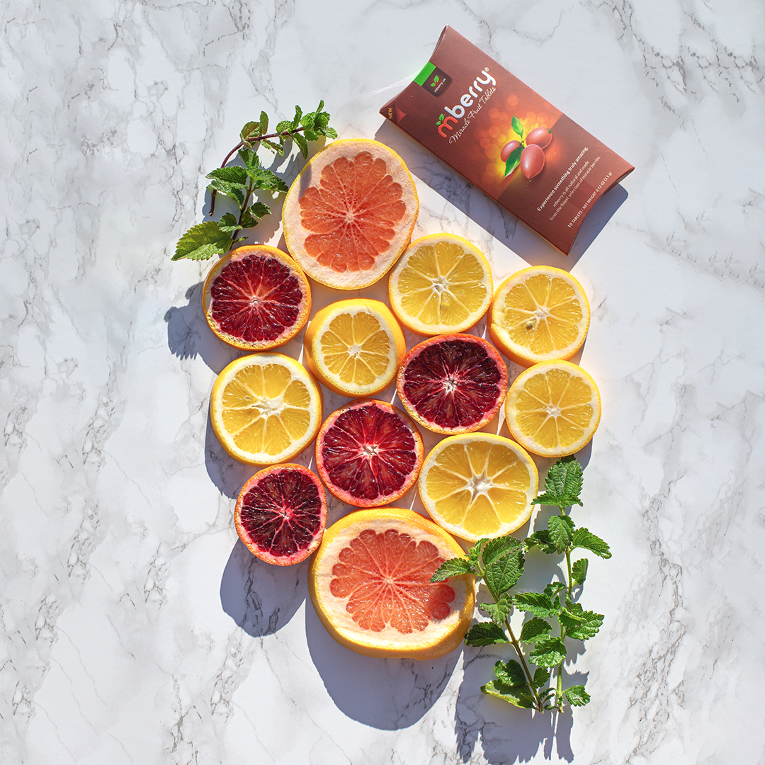 mberry miracle fruit tablets on marble slab next to an arrangement of blood oranges, lemons, grapefruit, and mint